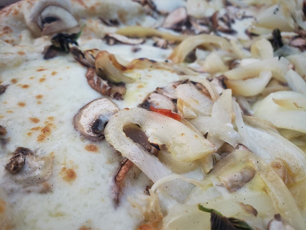 A close-up of Cugino Forno's wood fired creation is complete with Cipolini Onions, Mushrooms,...