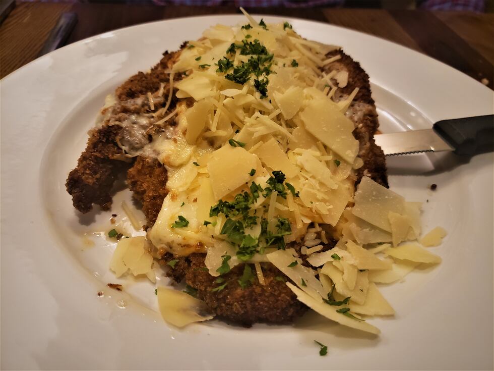 Veal cutlet fried crispy, topped with marinara sauce and mounds of cheese on top of a spaghetti.