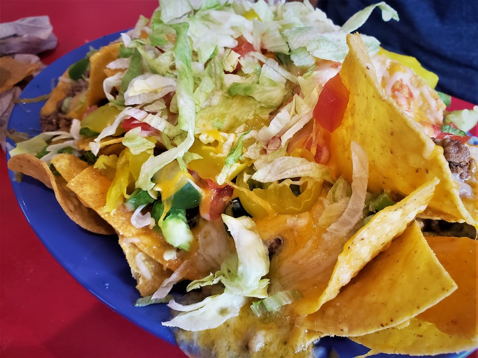 A mound of nachos piled high with cheese, veggies, sour cream and beef...plus you can lather...