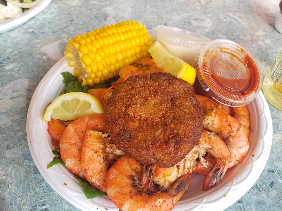 A plate stacked with steamed peel-and-eat shrimp and a homemade deviled crab cake...a classic...